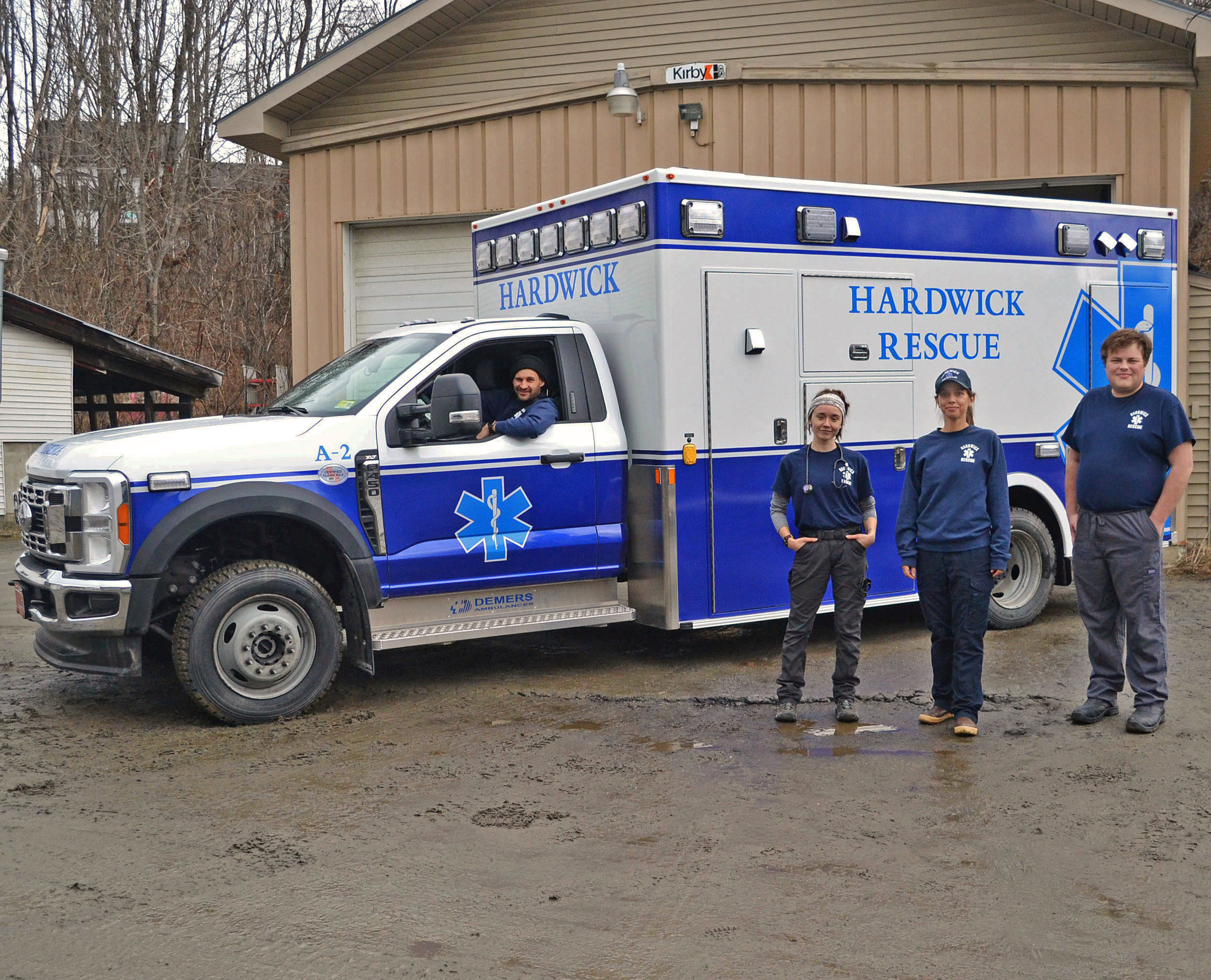 Photo of Hardwick Rescue's A-2 ambulance with a person in the drivers seat and three providers standing in front. Photo courtesy of Vanessa Fournier.